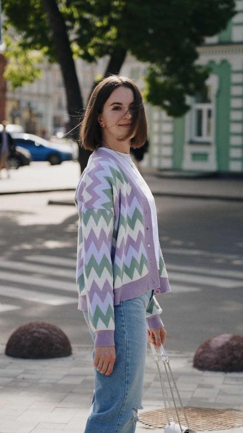 ผู้หญิงใส่คาร์ดิแกนลายซิกแซกโทนพาสเทลกับกางเกงยีนส์ฟอกอ่อน