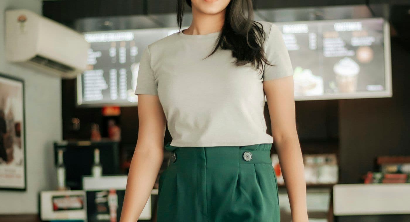 ผู้หญิงสวมเสื้อยืดสีขาวกับกางเกงขายาวสีเขียวเข้มทรงหลวม
